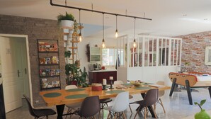 Un espace repas moderne avec une table en bois, plusieurs chaises et une table de baby-foot.