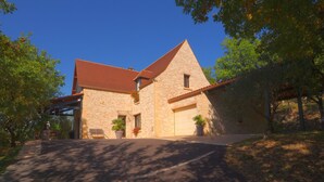 Un bâtiment en pierre avec un toit rouge, un garage et des plantes en pot.