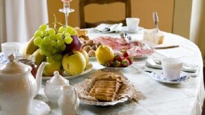 Una mesa de desayuno con una variedad de frutas, bollería y una tetera.
