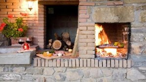Una chimenea de piedra con fuego encendido, rodeada por una pared de piedra rústica.