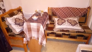 A cozy room with a wooden sofa and armchair, each with a plaid blanket and patterned pillows. A small table with a white ceramic top and a few jars is placed between them. - Comfortable apartment near the International Exhibition Center and  metro. (Київ)