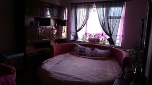 A bedroom with a large bed, a wooden wardrobe, and a window with curtains. - Comfortable apartment near the International Exhibition Center and  metro. (Київ)