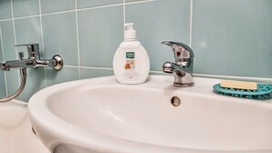 A bathroom sink with a chrome faucet, a soap dispenser, and a toothbrush holder. - Comfortable apartment near the International Exhibition Center and  metro. (Київ)