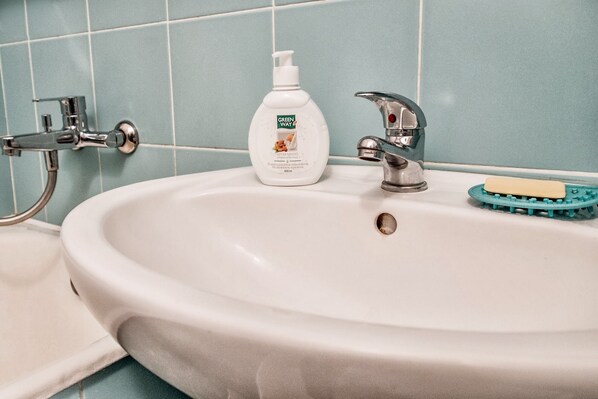 A bathroom sink with a chrome faucet, a soap dispenser, and a toothbrush holder.