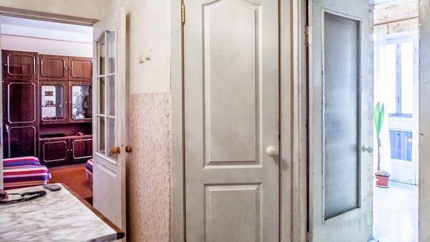 A hallway with a white door, a wooden cabinet, and a striped sofa. - Comfortable apartment near the International Exhibition Center and  metro. (Київ)