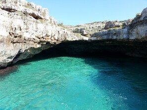 A natural cave entrance with clear turquoise water.