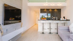 Una cucina moderna con TV integrata, sgabelli da bar e una grande isola.