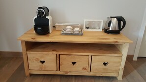 A wooden table with a coffee maker, a kettle, and a tray with cups.