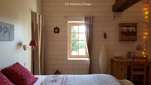 A bedroom with a bed, a window, a clock, a lamp, and a shelf with items.