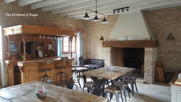 A rustic dining area with a wooden table and chairs, a bar area with a wooden counter, and a stone fireplace.