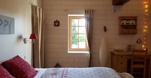 A bedroom with a bed, a window, a clock, a lamp, and a shelf with items.