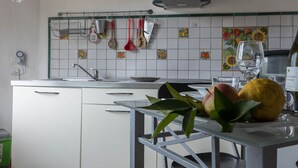 A kitchen with white cabinets, a stainless steel sink, and a hanging pot rack. - Apartment in studio villa called Vulcano sleeps 2 (REITANO)