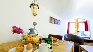 Una tavola imbandita per la colazione con croissant, uova, succo di frutta e una tazza verde.