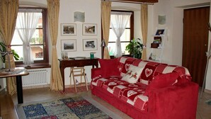 Ein gemütliches Wohnzimmer mit einem roten Sofa, einem Holztisch und einer Heizung.