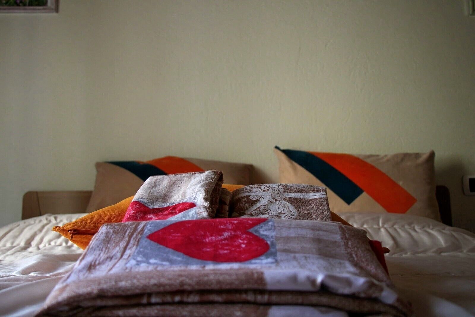 A neatly made bed with a white comforter and multiple pillows in various colors and patterns.