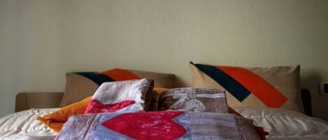 A neatly made bed with a white comforter and multiple pillows in various colors and patterns.