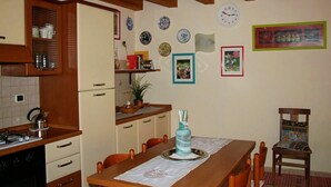 Eine Küche mit Holzausstattung, einem Esstisch mit Stühlen und verschiedenen dekorativen Tellern und Bildern an den Wänden.
