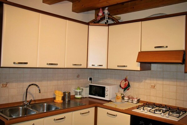 A kitchen with white cabinets, a stainless steel sink, a microwave, a gas stove, and a wooden ceiling. - APARTMENT by PAOLO LOVE AOSTA HISTORIC CENTER (Aosta)