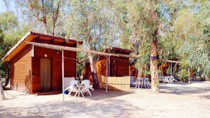 A wooden cabin with a covered porch and outdoor seating. - Camping la Naranja (Gandia)
