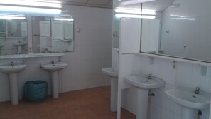 A public restroom with three sinks, mirrors, and a trash bin. - Camping la Naranja (Gandia)