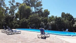 A swimming pool with lounge chairs and a stone-tiled deck. - Camping la Naranja (Gandia)