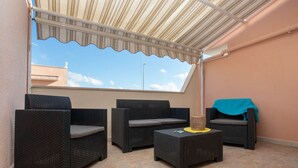 A covered outdoor seating area with wicker furniture and a small table. - Apartment for rent with terrace (TL66A) (Torre Lapillo)