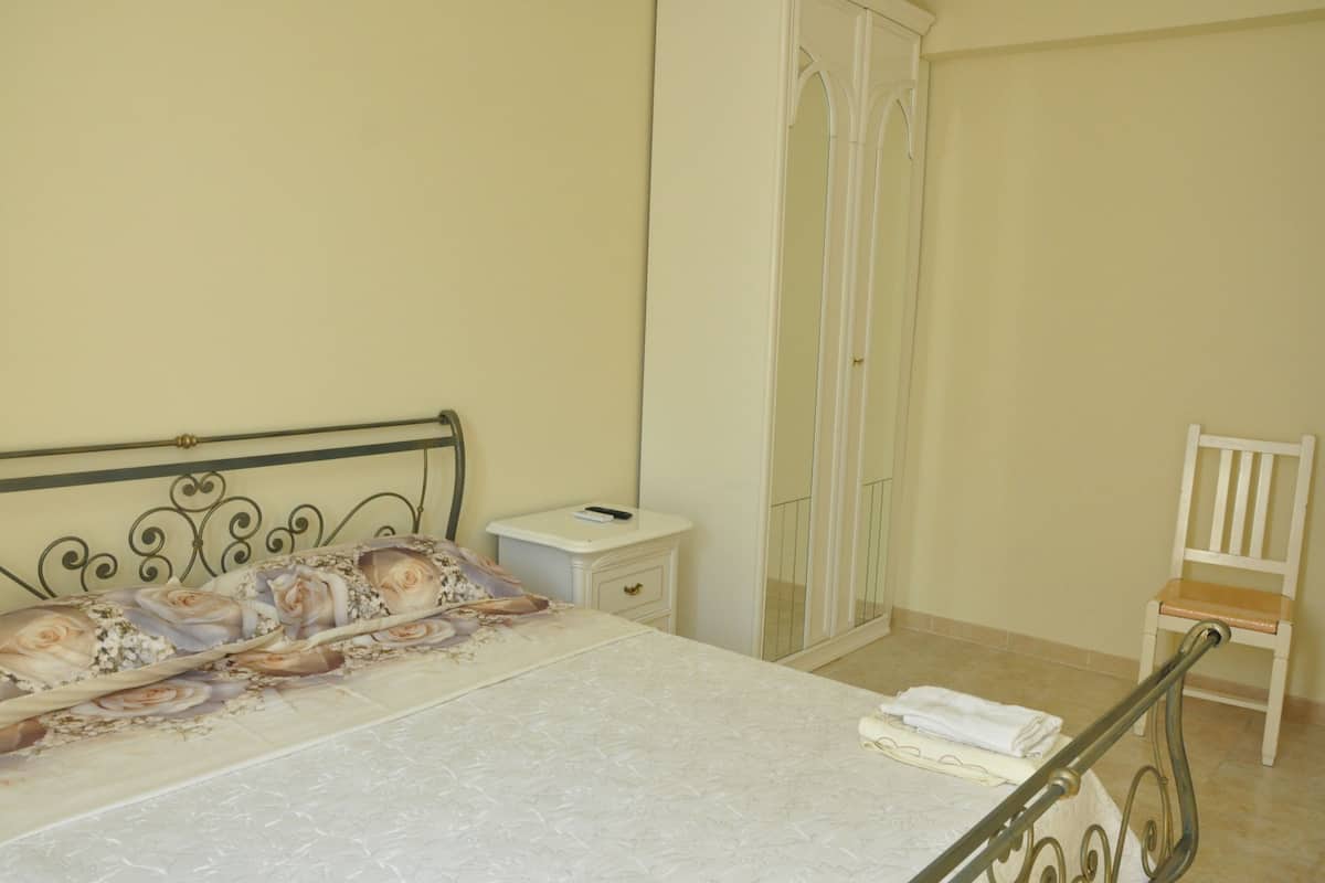 A bedroom with a bed, a nightstand, a wardrobe, and a chair.