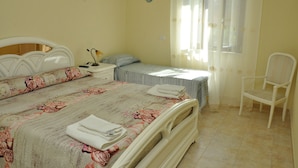 A bedroom with a large bed, a smaller bed, a chair, and a nightstand. - Victoria (Ercolano)