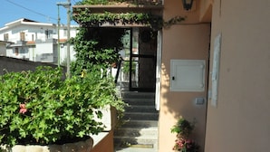 A balcony with a wooden bench, potted plants, and a staircase leading to a door. - Victoria (Ercolano)