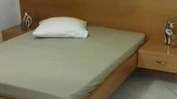 Un lit simple avec une tête de lit en bois et une table de chevet dotée d’un tiroir.