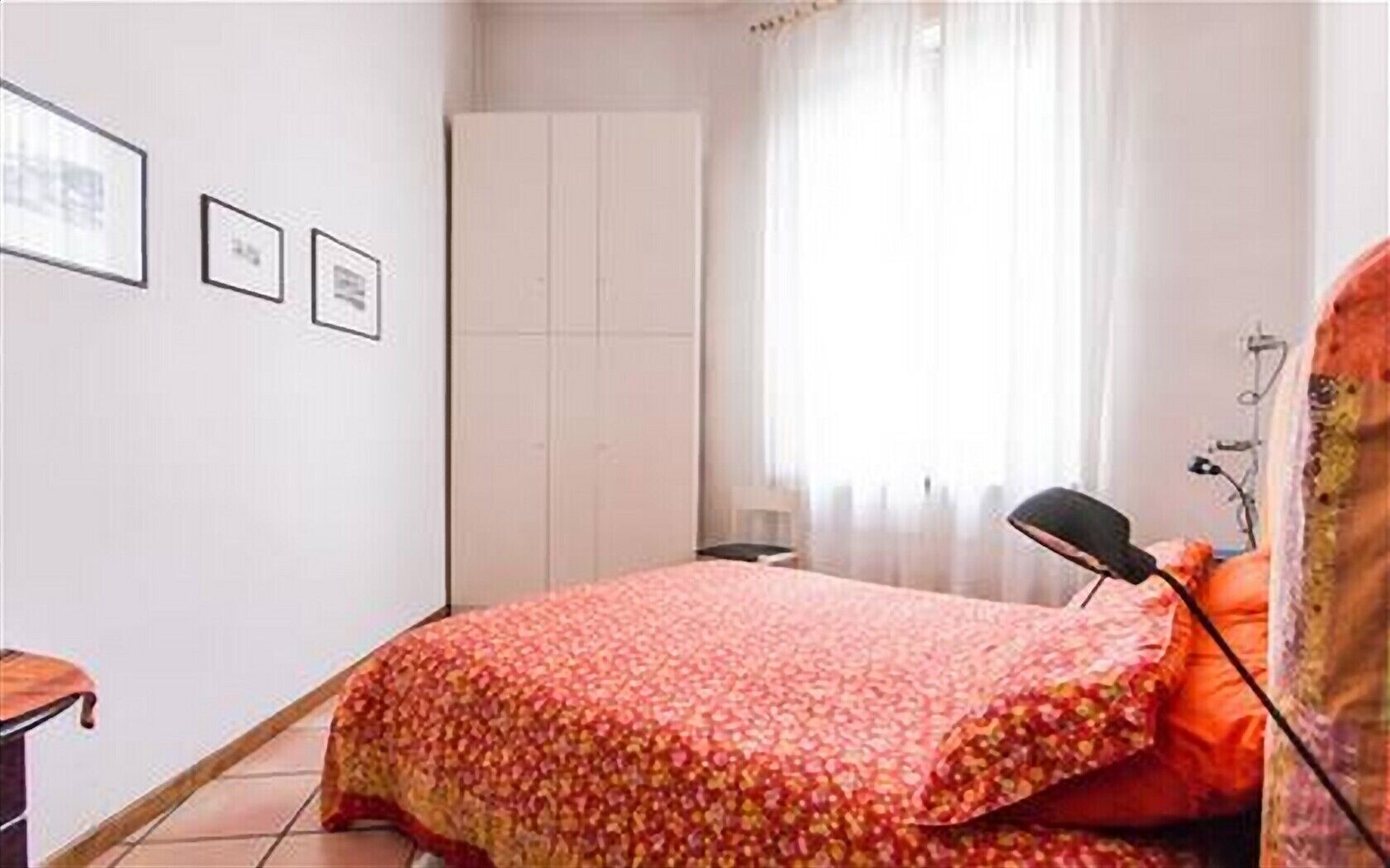Un dormitorio con cama, mesita de noche, lámpara y armario.