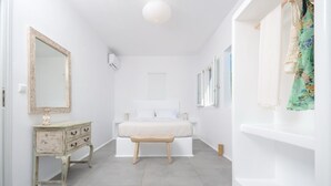 A bedroom with a bed, a dresser, a mirror, and a window. - Seaside Naxos • 2 Villas • 7 Bedrooms / 7 Bath • Sleeps 18 @ Plaka Baech (Naxos)