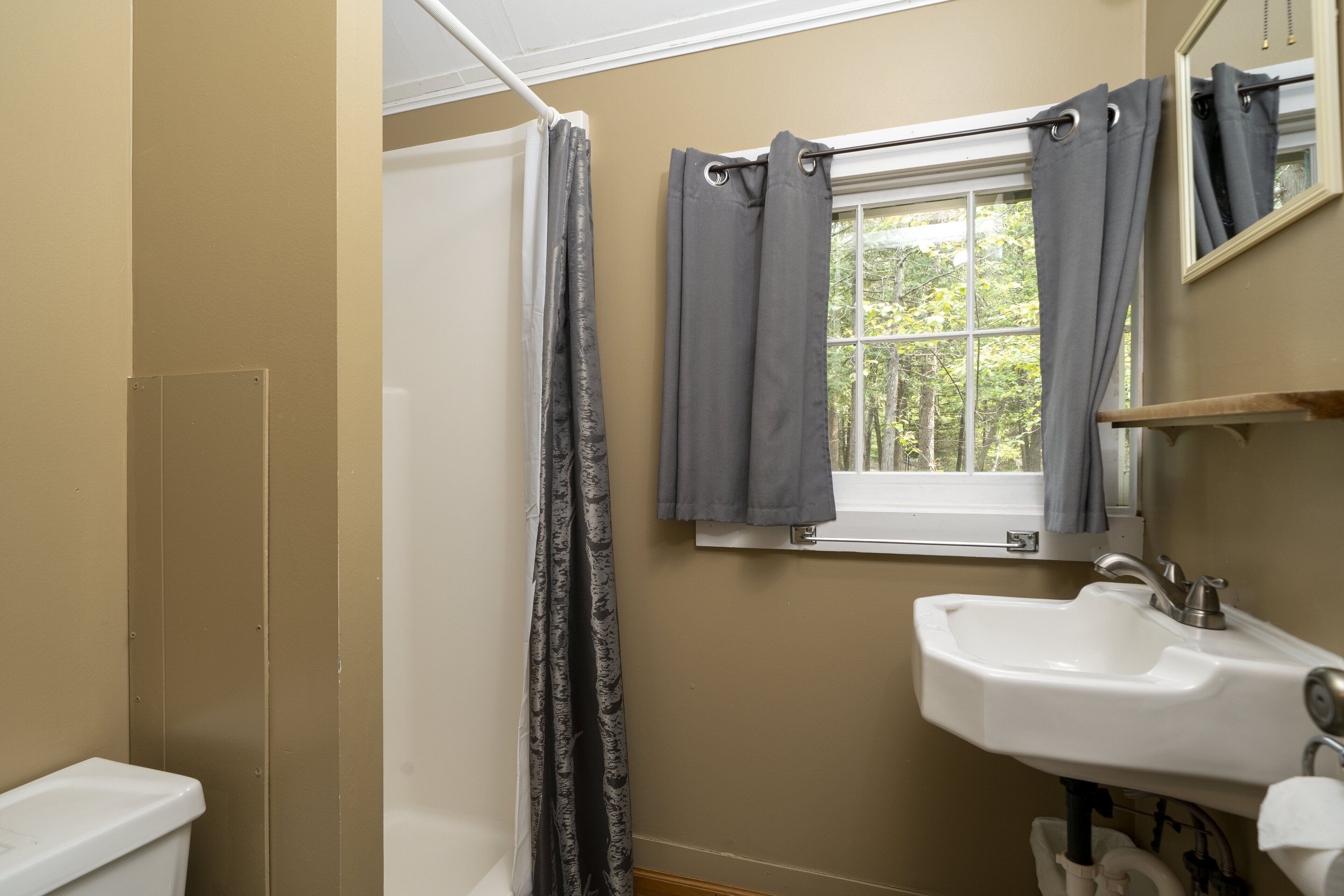 Une salle de bain avec une baignoire, un lavabo et une fenêtre avec des rideaux.