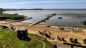 Propiedad frente al lago con muelle, barcos y una cabaña pequeña.