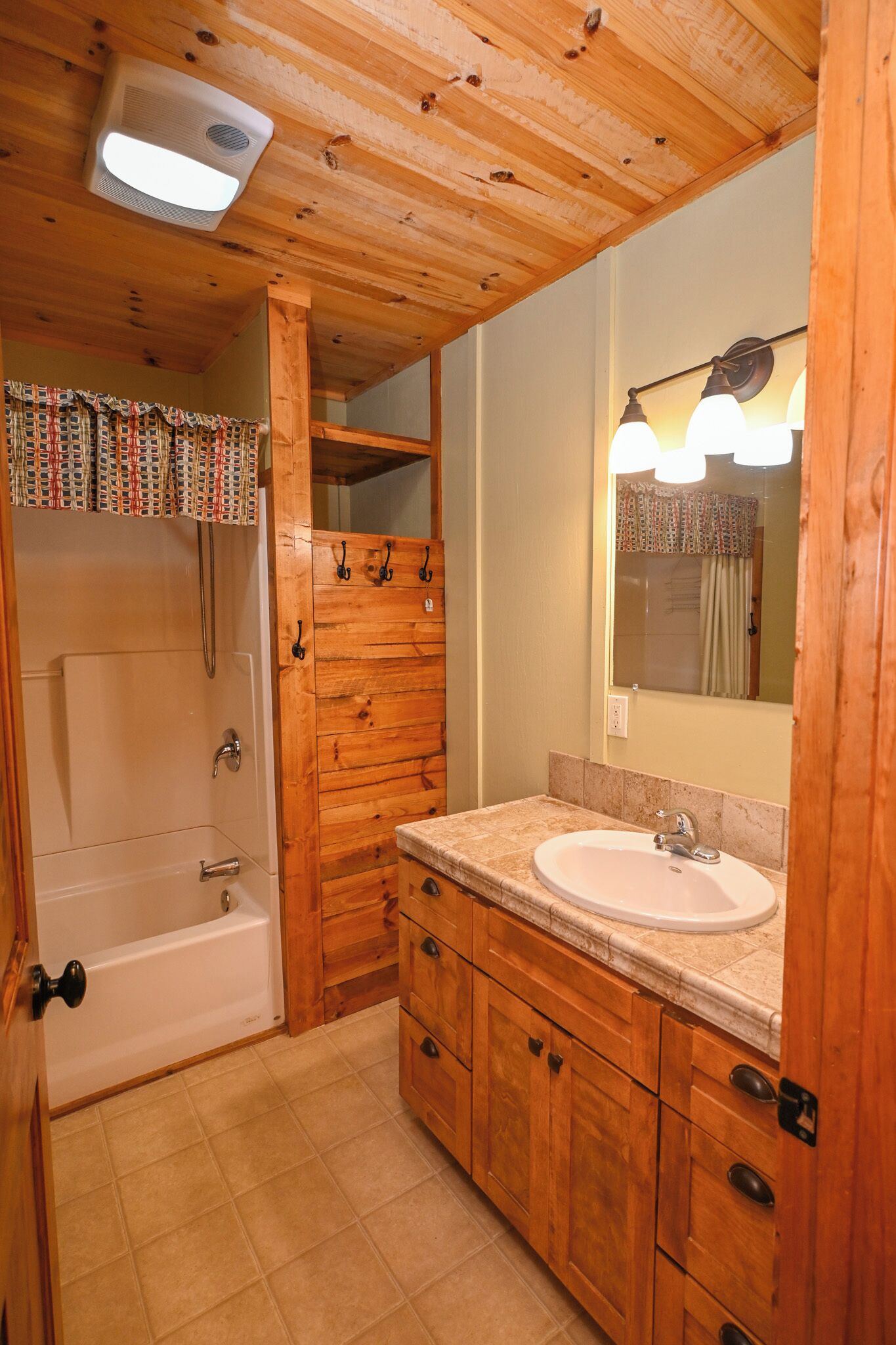 Un baño de madera con bañera, lavamanos y espejo.