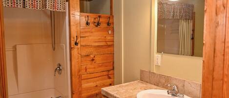 Un baño de madera con bañera, lavamanos y espejo.