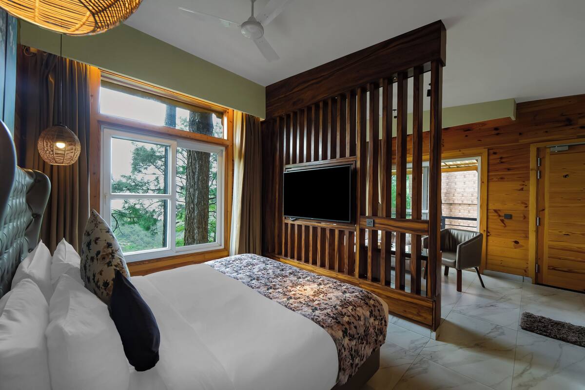 Quarto com uma cama grande, televisão e vista para o exterior.