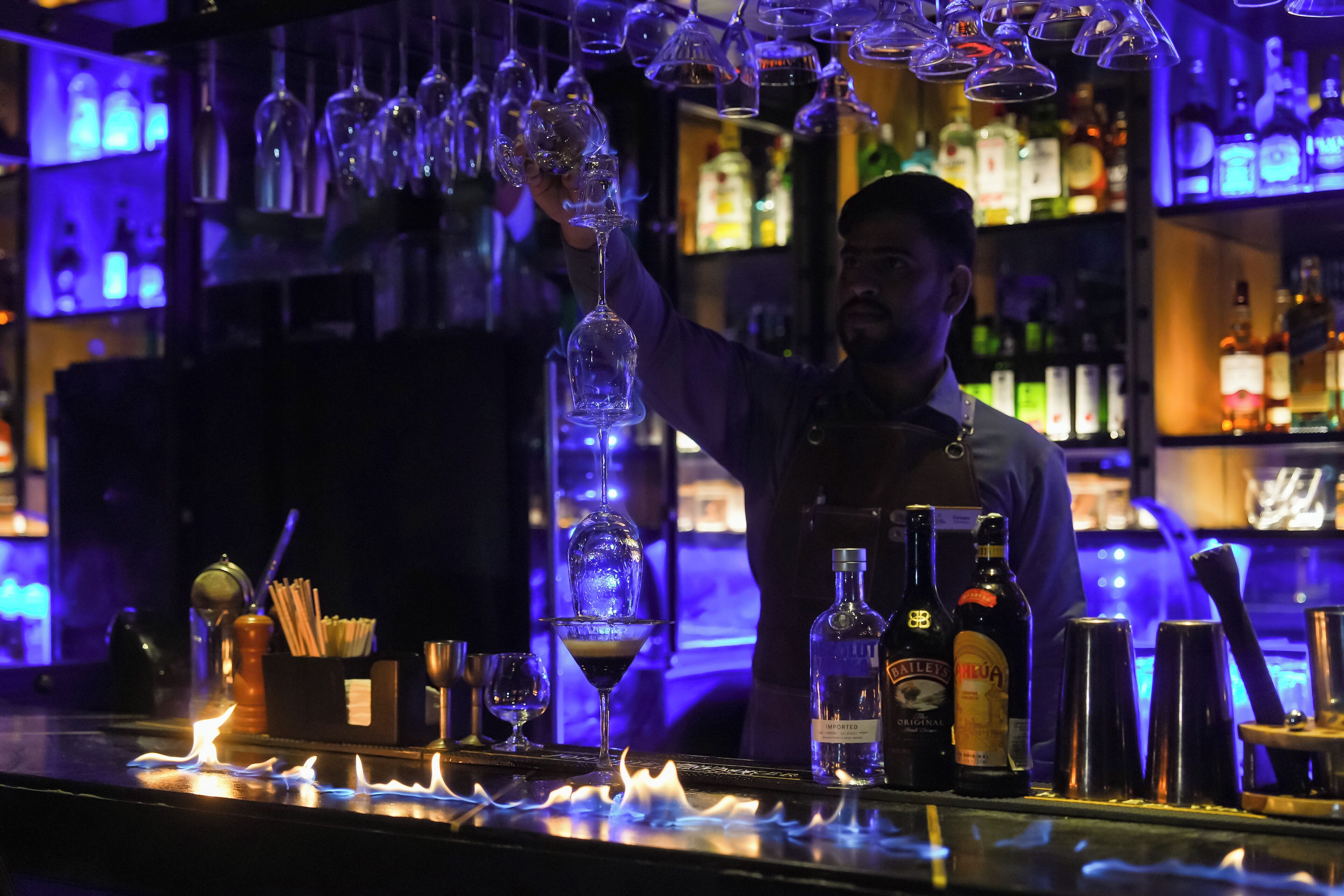 Eine Bar mit verschiedenen Flaschen und Gläsern, einer Kerze und einer Person, die ein Glas hält.
