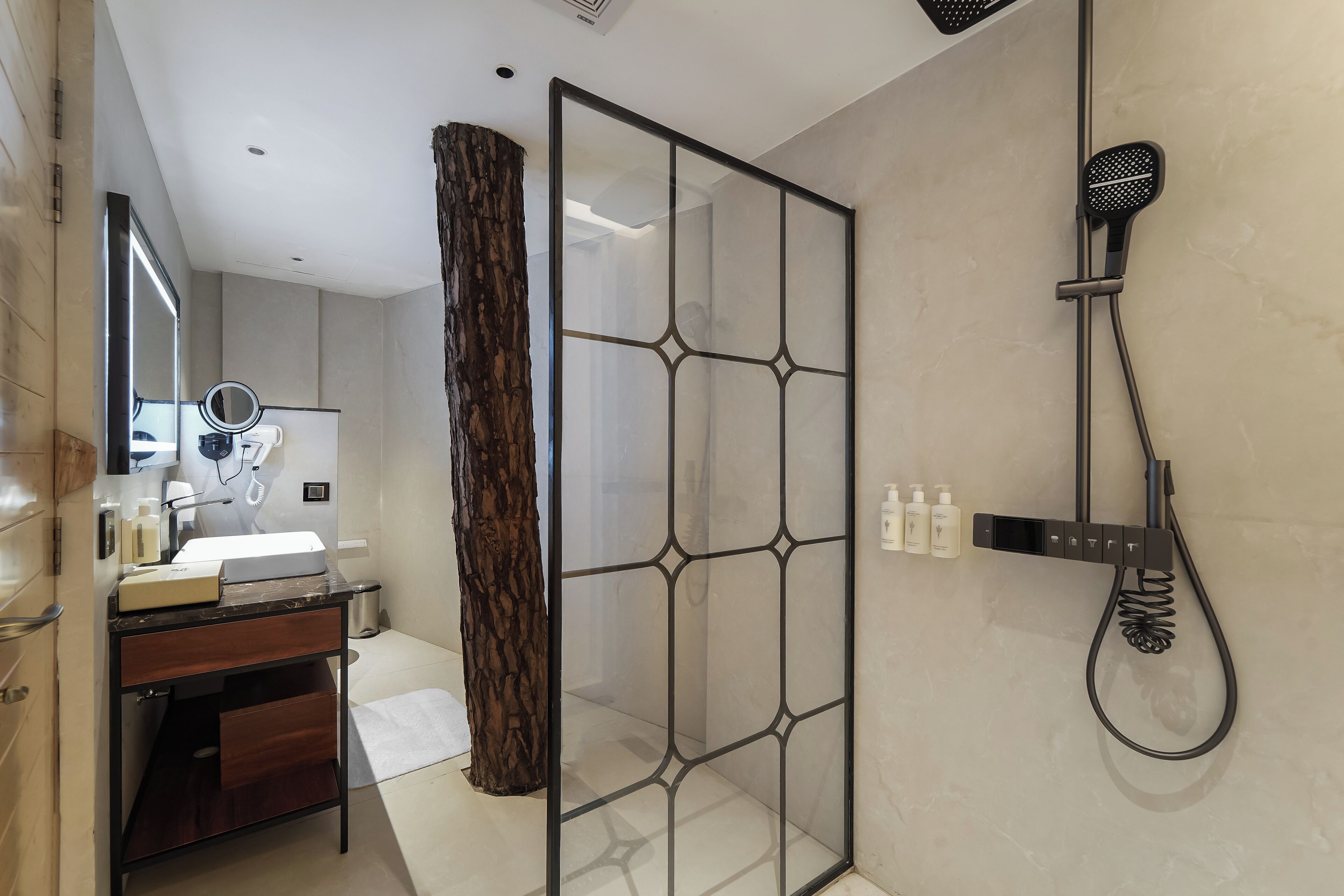 Un baño moderno con cabina de ducha de vidrio, tocador con espejo y secador de pelo montado en la pared.