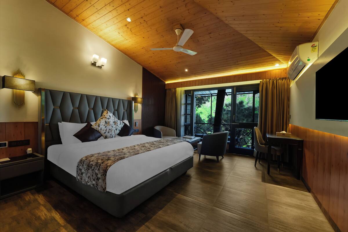 Quarto de hotel moderno com uma cama grande, uma escrivaninha e uma varanda com cortinas.