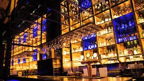 A bar with shelves of liquor bottles, a bar counter, and hanging light fixtures. - Kasauli Hills Resort (Kasauli)