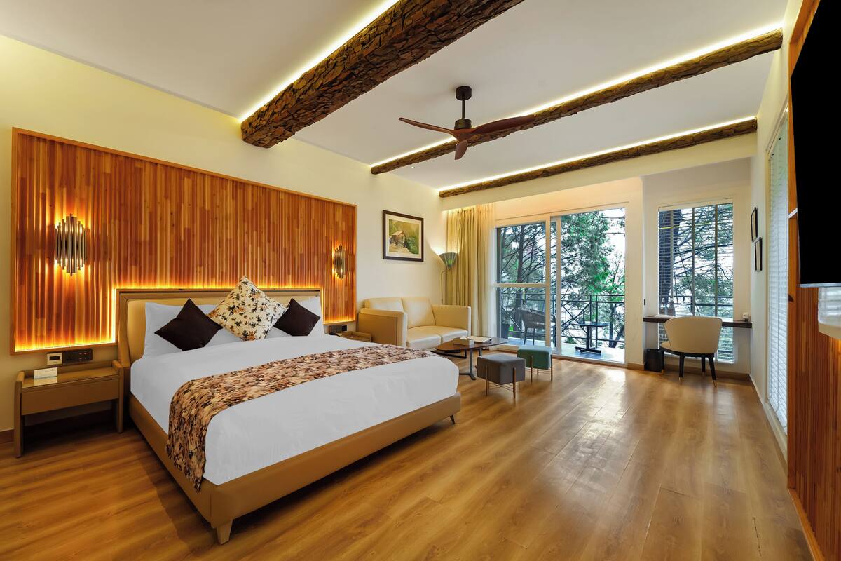 Quarto espaçoso com uma cama grande, ventilador de teto e vista para o exterior através de amplas janelas.