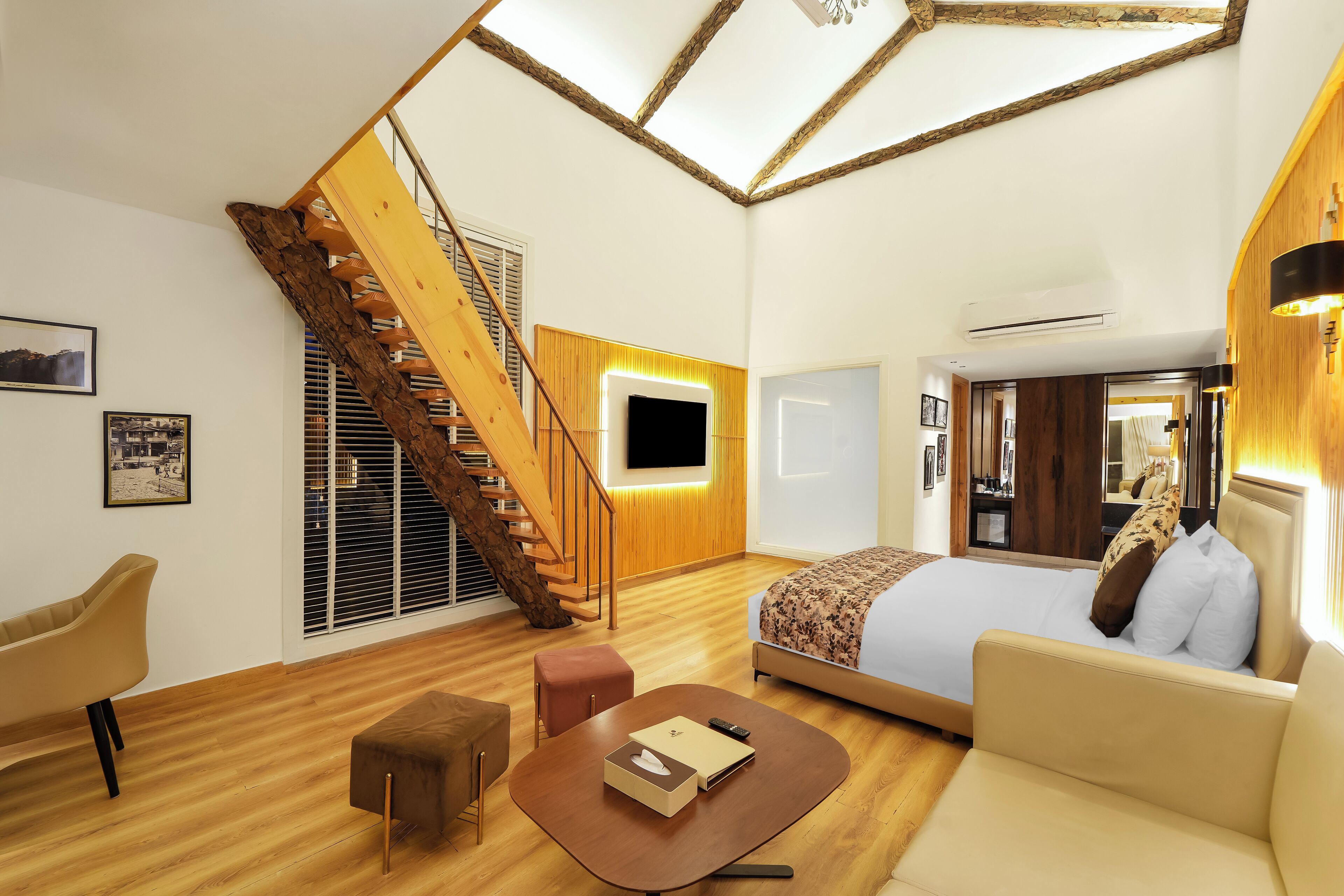 A modern room with a wooden staircase, a bed, a sofa, and a small table.