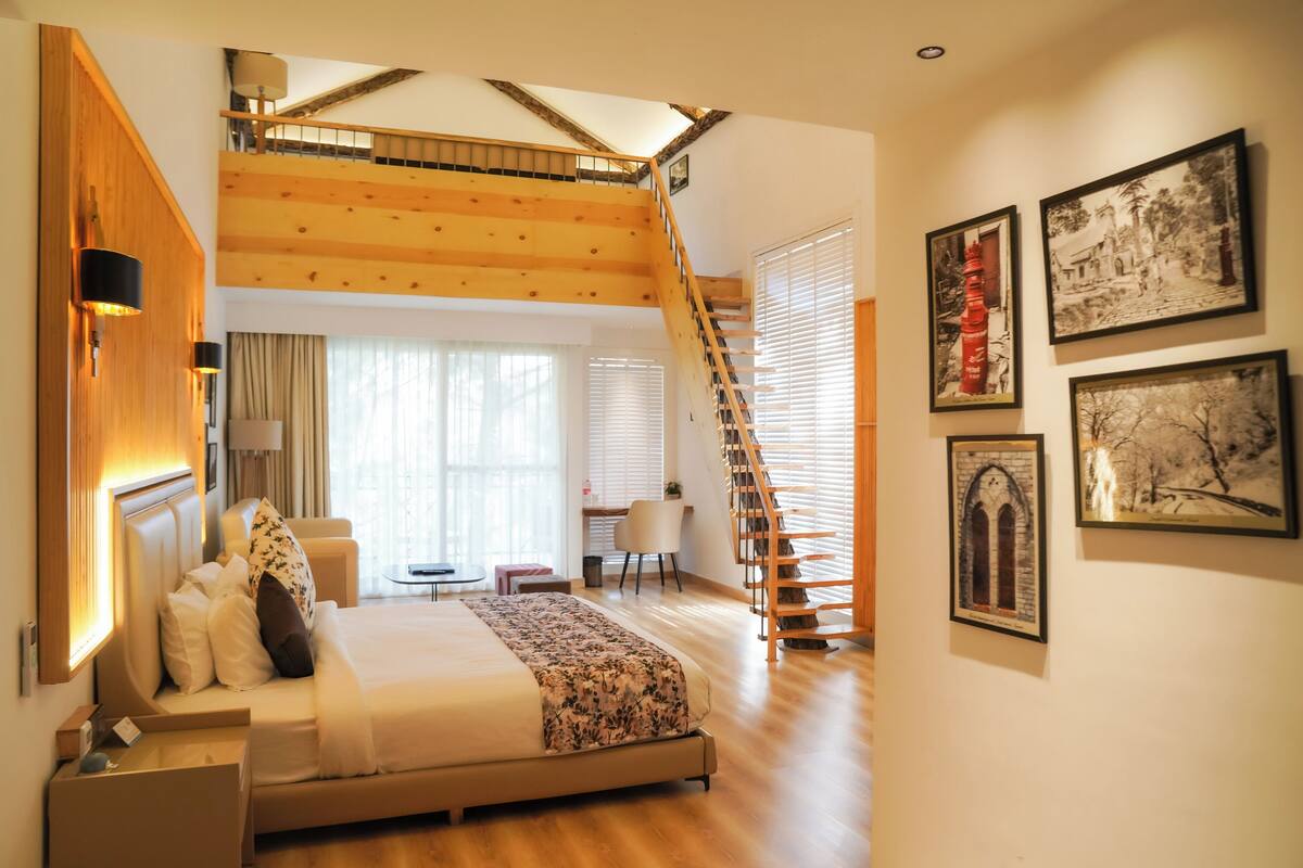 Um quarto espaçoso com uma cama grande, uma escada de madeira e um espaço para trabalhar.
