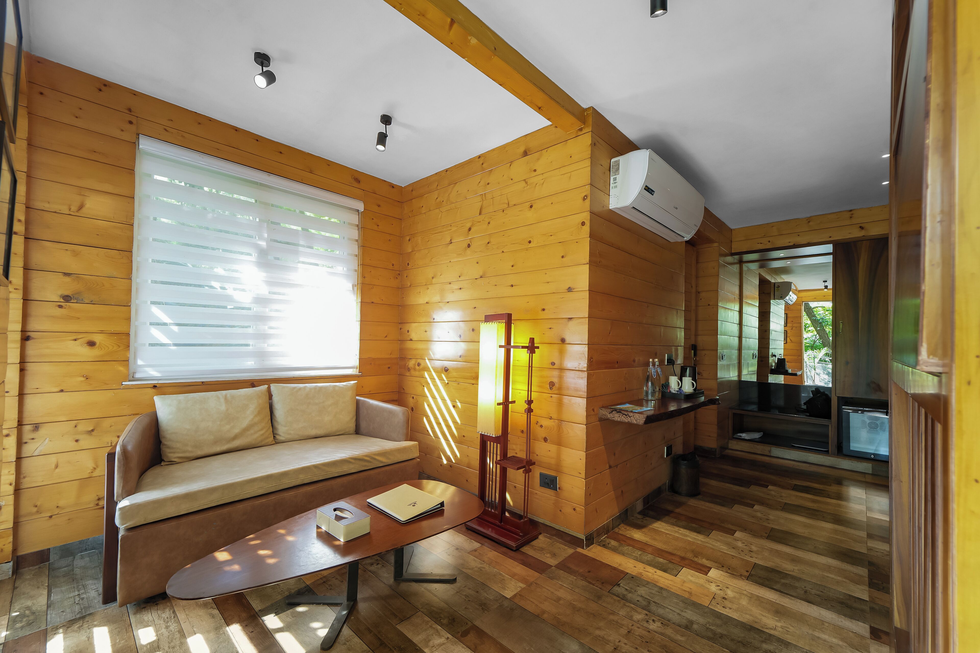 L’intérieur d’un chalet en bois chaleureux et accueillant, avec un canapé, une table et une lampe.