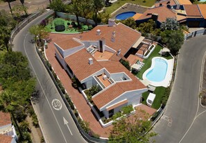An aerial view of a residential property with a swimming pool, a tennis court, and a curved driveway. - Casa Gran Canaria - Private heated pool, games room and playground (San Bartolomé de Tirajana)