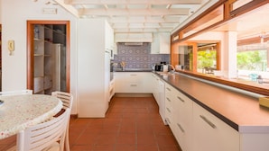 A compact kitchen with white cabinets, a tiled backsplash, and a window overlooking a garden.