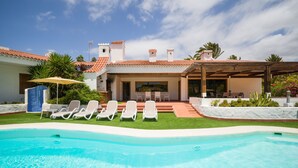 A poolside area with lounge chairs and a covered patio.