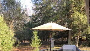 Una terraza de madera con una mesa, sillas, una parrilla y un paraguas.
