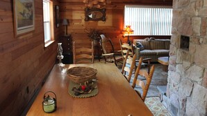 Un interior de madera con una mesa de comedor, sillas, chimenea y un sofá.